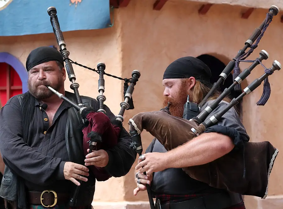 Two bearded men playing bagpipes at renfest